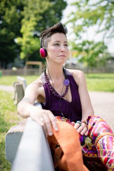 beautiful hipster short hair woman listening music in the park in the city