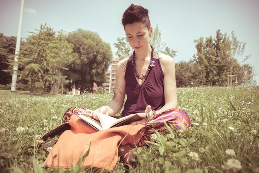 beautiful hipster short hair woman reading book in the park in the city