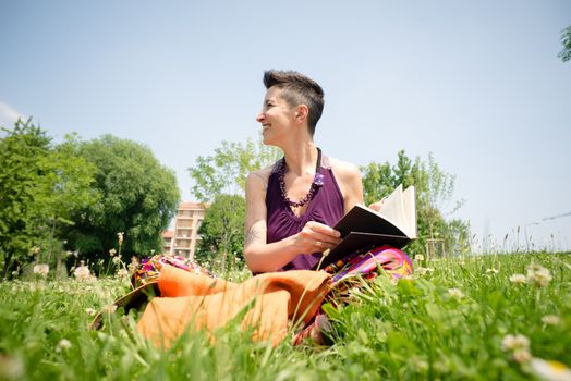 beautiful hipster short hair woman reading book in the park in the city