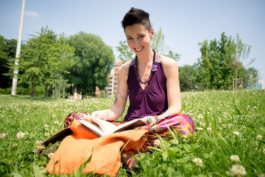 beautiful hipster short hair woman reading book in the park in the city