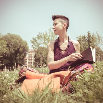 beautiful hipster short hair woman reading book in the park in the city