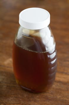 Jar of fresh honey on the wooden tabletop.
