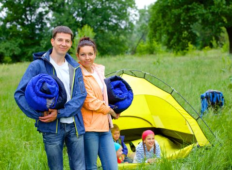 Young happy couple camping near tent in park