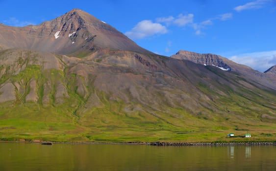 Iceland summer landscape. Fjord, house, mountains. Panorama.