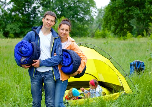 Young happy couple camping near tent in park