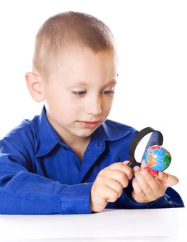 Schoolboy with a magnifying glass carefully consider Globe