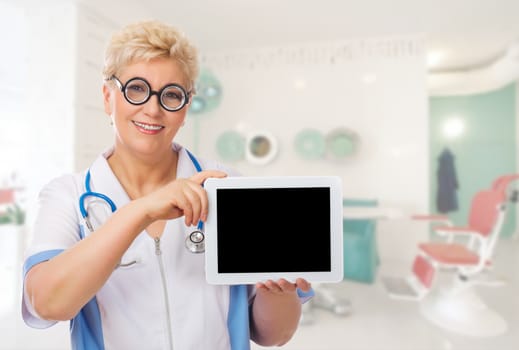 Mature doctor with funny glasses and tablet PC at medical office