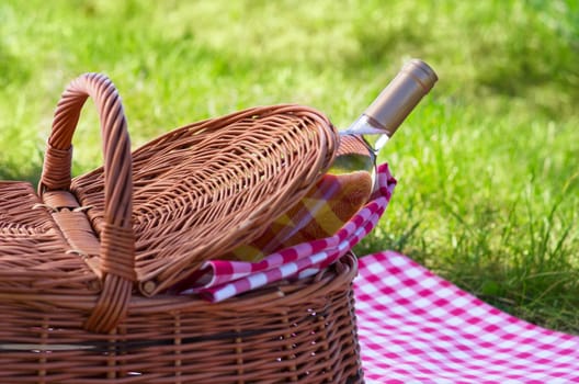 Wine bottle with picnic basket on plaid