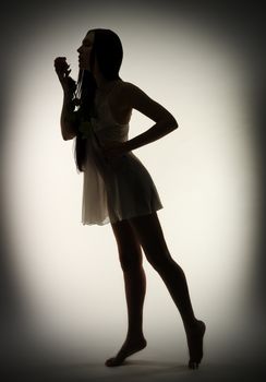 Silhouette of young girl with rose flower on gray background