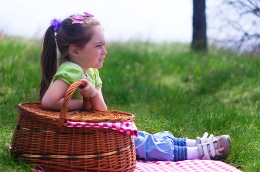 Little smiling girl with picnic basket at forest