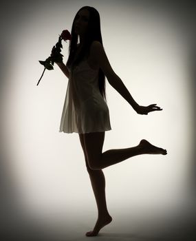 Silhouette of young girl with rose flower on gray background