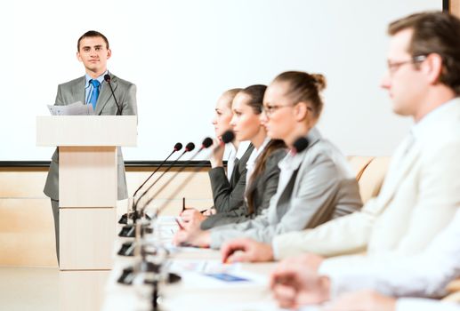 businessmen communicate at the conference, sitting at the table, on the table microphones and documents