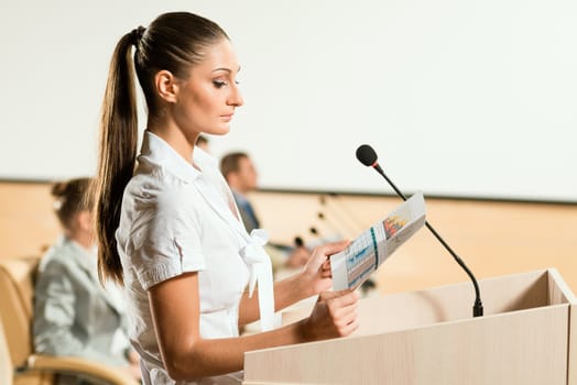 Portrait of a business woman holding a microphone and looks ahead