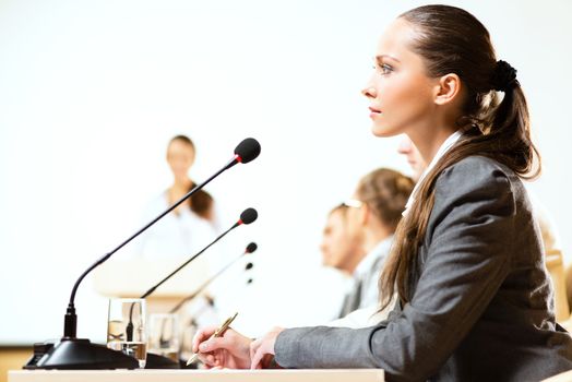 businessmen communicate at the conference, sitting at the table, on the table microphones and documents