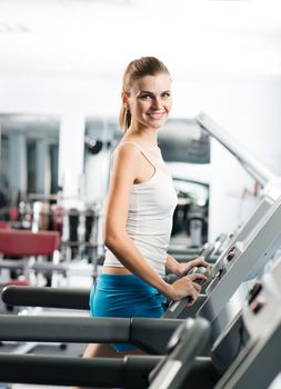 attractive young woman runs on a treadmill, is engaged in fitness sport club