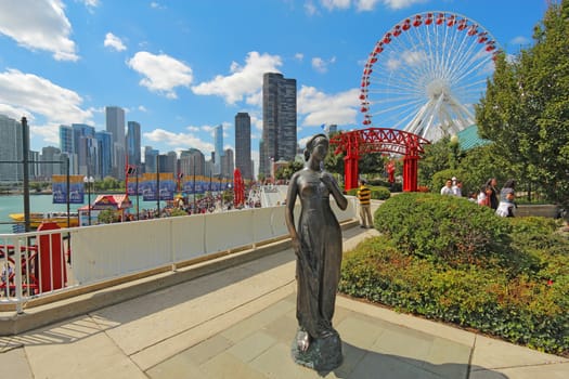 CHICAGO, ILLINOIS - SEPTEMBER 4: Statue, tourists and rides at the Navy Pier in Chicago, Illinois on September 4, 2011. The Pier is a popular destination with many attractions on Lake Michigan.