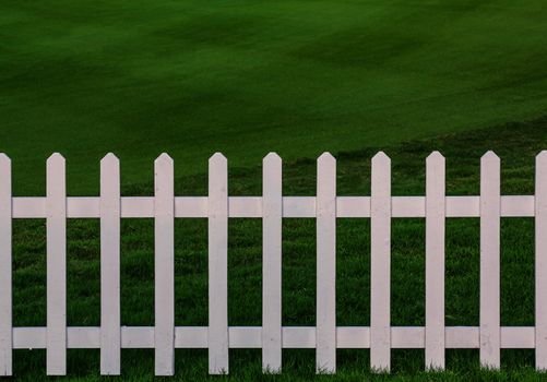 Green lawn and white wood fence