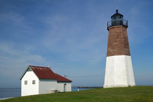 The Point Judith light and associated buildings near Narragansett, Rhode Island, against a bright blue sky and whispy white clouds