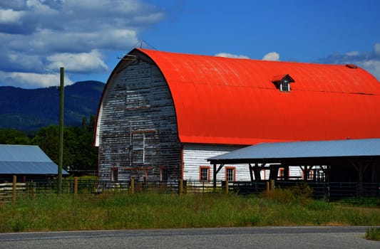 White barn with red roof on side of road