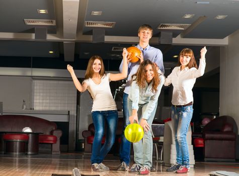 Group of young friends playing bowling, spending time with friends