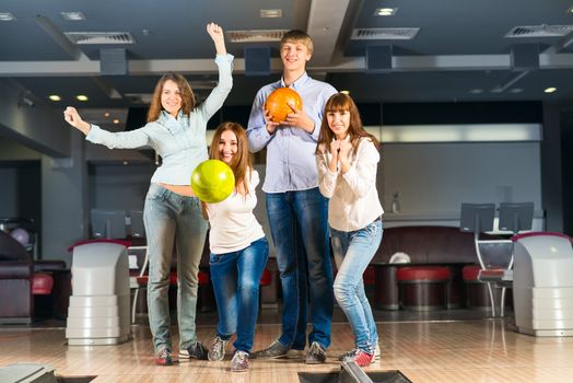 Group of young friends playing bowling, spending time with friends