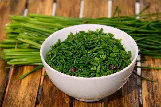 A white bowl with cutted chives on a table