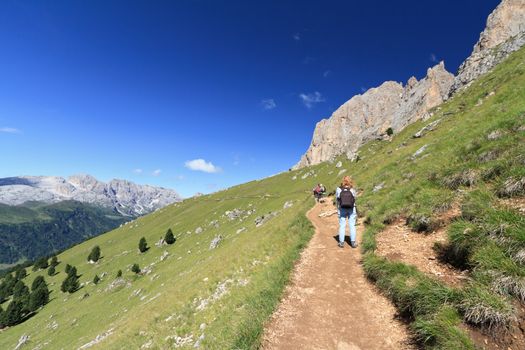 hiking beneath Sassolungo group on summer, Trentino, Italy