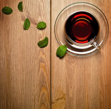 Tea mint in glass cup with fresh mint leaves on wooden background. Top view