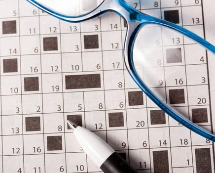 Pen and glasses on the newspaper with crossword