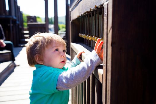 A young boy plays some sort of bells musical instrument at the playground in a park outdoors.