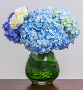 Blue Hydrangea bouquet in glass vase on wood table