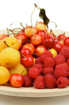 Heap of Juicy Apricots, Sweet Cherries and Raspberries on Wooden Plate closeup