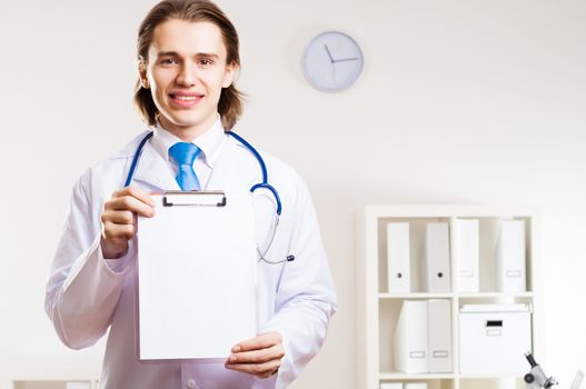 Doctor holding a clipboard with a clean sheet of paper, place for text