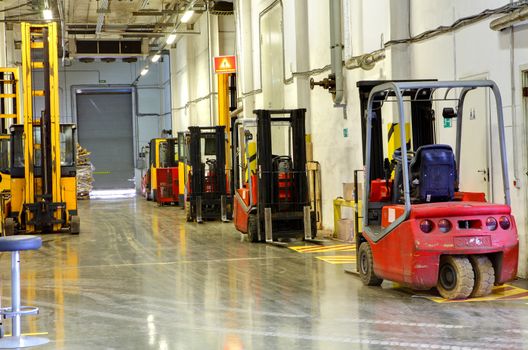 Interior Storage terminal with loaders, standing along the walls. Corridor large warehouse. Forklift Trucks in stock. 