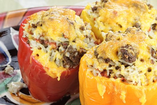 Three colorful baked stuffed peppers with beef, rice, vegetables and cheese.
