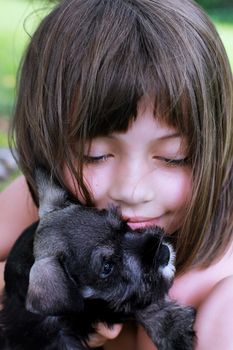 Little girl hugging her Mini Schnauzer puppy. Extreme shallow depth of field with selective focus on child's face.