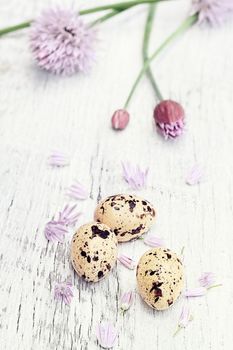 Quail eggs with freshly cut organic chives lying on a wooden background. 