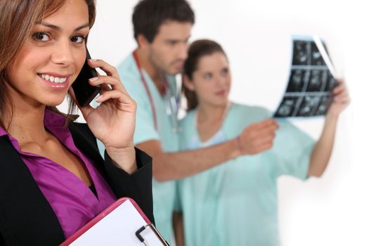 Hospital manager on a phone as medics look at x rays in the background