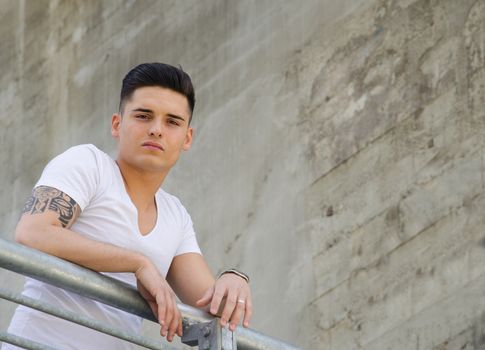 Good looking young man in urban setting, looking down from metal railing