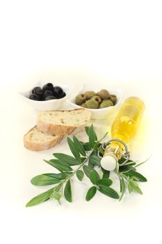 Bottle of olive oil with fresh olives, baguette and olive branch on a bright background