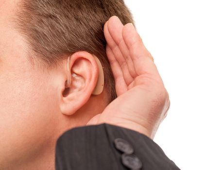 Close up ear of a middle aged businessman wearing hearing aid and listening for a sound.