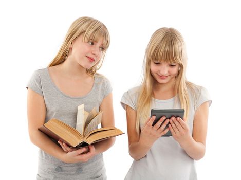 Ebook or book - Girl holding a big book looking at another girl enviously who is reading an ebook with her ebook reader.