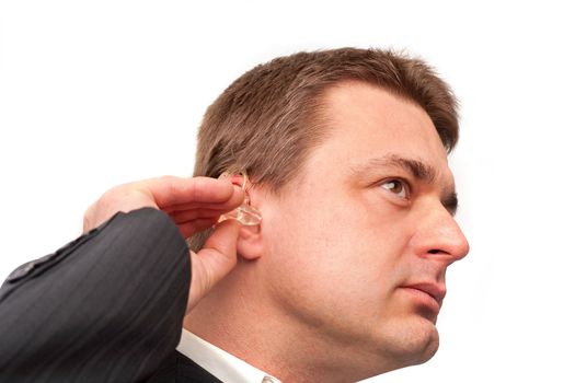 Man putting on a hearing aid isolated on white
