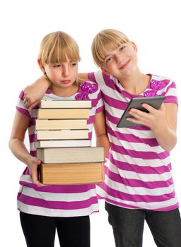 Books vs ebook reader - Two girls demonstrating the difference. One of them holding lots of books while another reading an ebook reader and smiling.