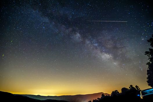 Milky way over the city lights and mountains on blue ridge parkway