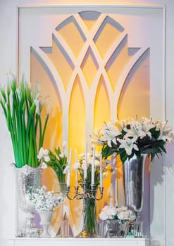 White flowers such as Calla lily and rose with candles and sconce on white window