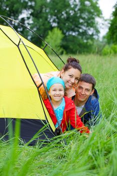 Summer vacation. Family of three in tent in camping on the nature. Vertical view