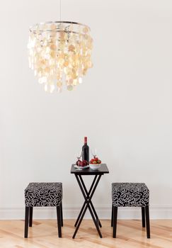 Table for two with bottle of red wine, in a room decorated with beautiful chandelier.