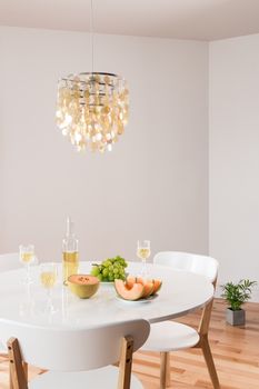 White wine and fruits on a table. Room decorated with beautiful chandelier.