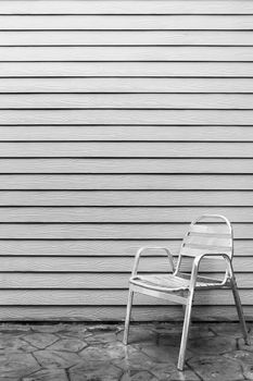 Wet lonely metal chair outside the house after raining